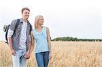 Young hiking couple holding hands while standing on field