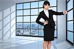 Focused businesswoman pointing against room with large window showing city