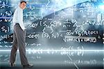 Happy businessman standing with hands in pockets against math equation background