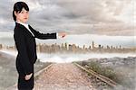 Focused businesswoman pointing against stony path leading to large urban sprawl