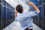 Businessman posing with arms raised against server hallway in the sky