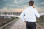 Thinking businessman touching his chin against stony path leading to large city on the horizon