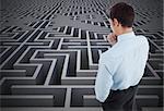 Thoughtful businessman with hand on chin against difficult maze puzzle