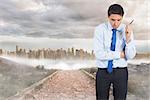 Thinking businessman holding pen against stony path leading to large urban sprawl