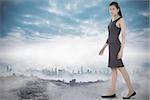 Asian businesswoman walking against dusty path leading to city under the clouds