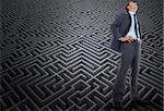 Happy businessman with hands on hips against difficult maze puzzle