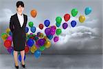 Businesswoman standing against many colourful balloons in cloudy room