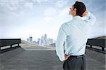 Thinking businessman with hand on head against road leading out to the horizon