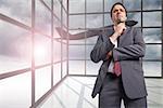 Thinking businessman holding his glasses against airplane flying past window