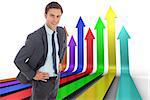 Cheerful businessman standing with hands on hips against colourful arrows pointing up