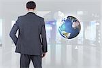 Businessman standing with hand on hip against global business hologram