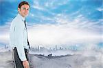Happy businessman standing with hand in pocket against dusty path leading to city under the clouds