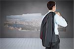 Businessman holding his jacket against display on wall showing city view