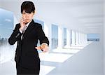 Thoughtful businesswoman pointing against bright white hall with columns