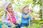 Cute Young Brother and Sister Enjoying Their Easter Eggs Outside in the Park Together.