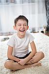 Smiling boy indoor. Sitting on the floor