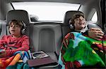 Brothers in back seat of car, wearing headphones