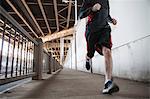 Cropped shot of young man running on city bridge