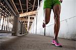 Cropped shot of young woman running on city bridge