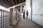 Young couple running on city bridge