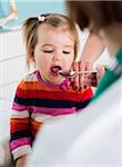 Doctor giving Baby Girl Spoonful of Medicine in Doctor's Office