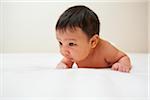 Newborn Asian baby with baby acne lying on stomach, studio shot on white background