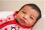 Close-up portrait of two week old Asian baby girl in pink polka dot jacket, studio shot