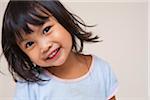 Close-up portrait of Asian toddler girl, looking at camera and smiling, studio shot on white background