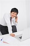 Portrait of happy mid adult businessman using cell phone at desk