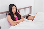 Portrait of displeased woman with man sleeping in bed
