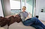 Relaxed mid-adult man reading book in living room at home