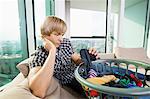 Tired man with laundry basket sitting on sofa at home