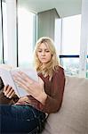 Relaxed young woman reading book in living room at home