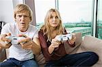 Young couple playing video game in living room at home