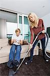 Woman vacuuming while man play video game in living room at home