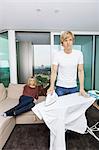 Man ironing shirt while woman sitting on sofa at home