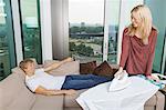 Smiling woman looking at relaxed while ironing shirt in living room at home