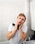 Portrait of man with hairbrush grimacing in bathroom