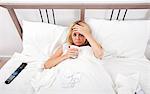 Portrait of woman suffering from cold having coffee in bed