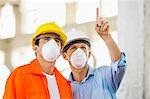 Male architects wearing protective mask while working at construction site