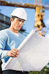 Male architect examining blueprint at construction site
