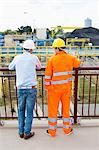 Back view of architects standing against railing at construction site