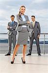 Portrait of confident businesswoman standing with coworkers on terrace against sky