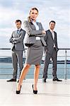 Full length portrait of confident businesswoman standing with coworkers on terrace against sky