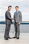 Full length portrait of businessmen shaking hands on terrace