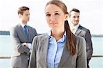 Portrait of confident businesswoman standing with coworkers in background on terrace