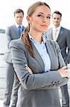Portrait of confident businesswoman standing arms crossed with coworkers in background on terrace