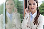 Beautiful businesswoman answering cell phone by glass door