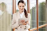 Beautiful businesswoman using digital tablet against office building