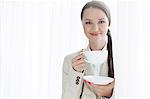 Portrait of businesswoman having coffee in office